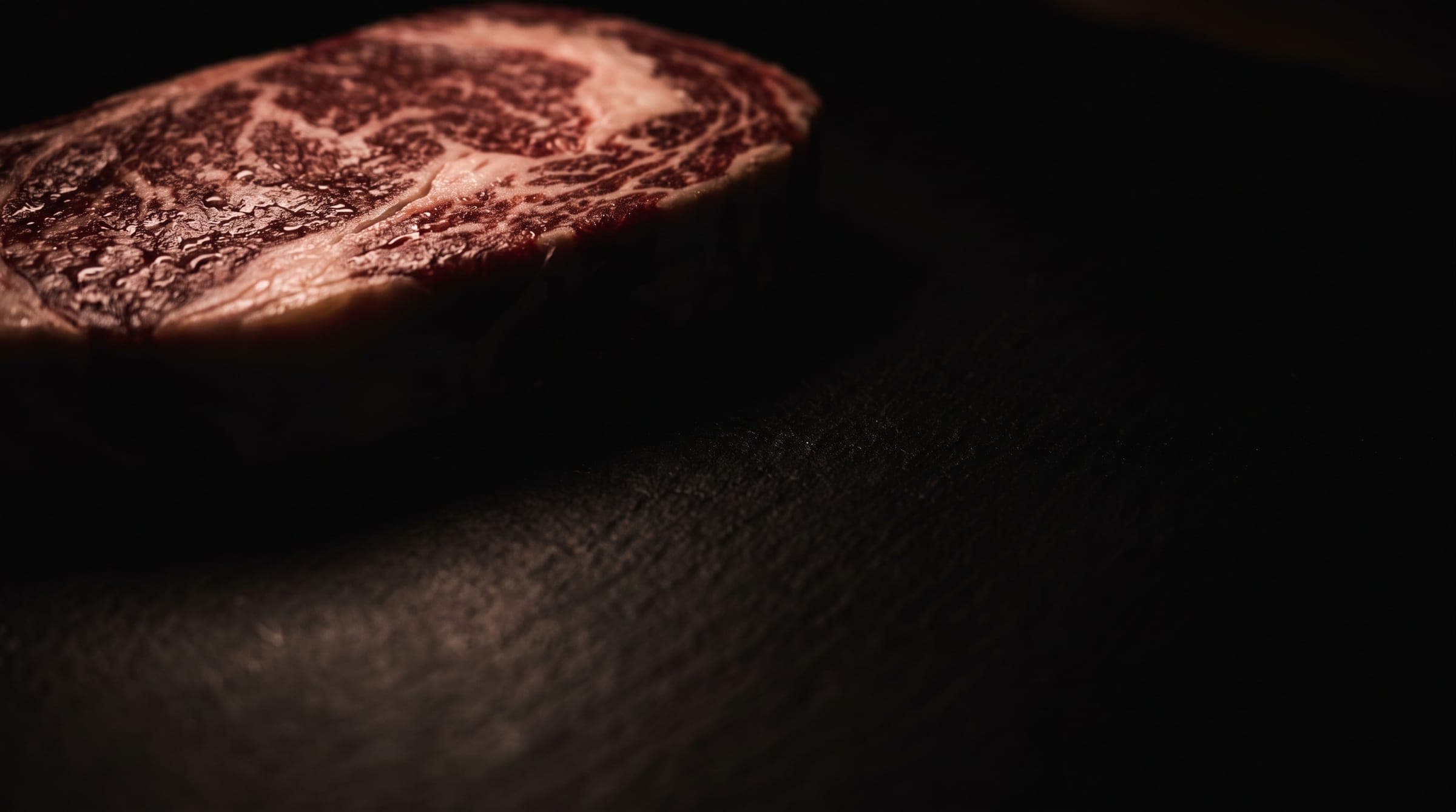 Rauwe, sterk gemarmerde steak op een donkere stenen plaat